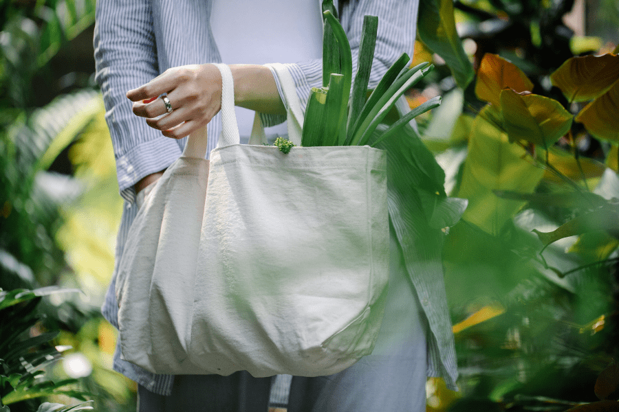 una mujer busca algo dentro de su bolsa de tela reutilizable