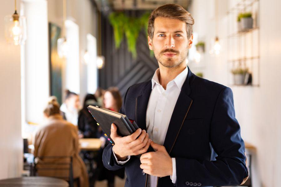 empresario en primer plano con libreta y oficina con gente de fondo